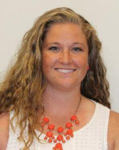 Casey Hare - woman with long blonde hair, white short sleeved shirt and orange necklace